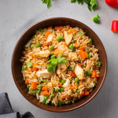 Flavorful Chicken Fried Rice, featuring tender pieces of chicken, fluffy rice, and a mix of vegetables stir-fried to perfection in a savory soy sauce. This quick and easy recipe is ideal for busy weeknights, combining garlic, ginger, and sesame oil for authentic Asian-inspired flavors. Ready in minutes, this dish is a satisfying, one-pan meal that's perfect for lunch, dinner, or meal prep