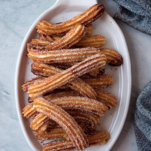 Golden, crispy Churros coated in cinnamon sugar, featuring a crunchy exterior and soft, airy inside. These classic, deep-fried dough treats are perfect for dipping in chocolate sauce or caramel, offering a delightful combination of sweet and savory flavors. Whether enjoyed as a dessert or a fun snack, churros are a crowd-pleaser that’s ideal for parties, fairs, or cozy nights in.