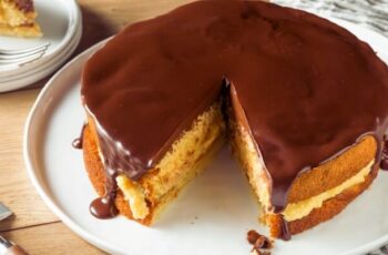 A traditional Boston Cream Pie is a delicious dessert made of soft layers of vanilla sponge cake. These layers are filled with creamy pastry and finished off with a glossy layer of chocolate ganache on top.