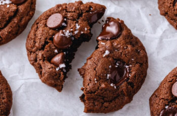 Decadent double chocolate chip cookies, freshly baked to perfection. Each cookie boasts a rich, cocoa-infused dough, studded generously with dark chocolate chips that melt in every bite. The cookies are slightly crisp on the edges, yet irresistibly chewy and soft in the center, creating a delightful contrast in texture. With a tantalizing aroma of cocoa wafting through the air, these indulgent treats promise a symphony of deep, intense chocolate flavors that delight the senses.