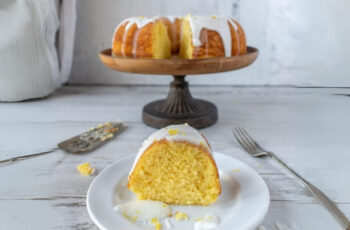 Deliciously golden lemon bundt cake dusted with powdered sugar. The moist crumb boasts a zesty aroma, with a delicate balance of tangy lemon flavor and a hint of sweetness. The cake's intricate bundt shape is adorned with a drizzle of lemon glaze, offering a tantalizing visual contrast against its textured surface. This delectable dessert promises a delightful burst of citrus in every bite, perfect for any occasion.