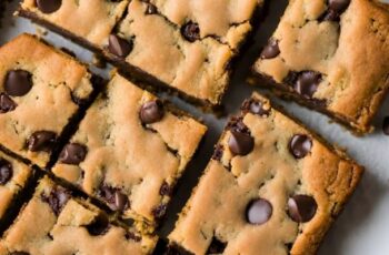 Scrumptious brown chocolate chip blondies, offering a delightful twist on the classic brownie. These golden bars boast a buttery and vanilla-infused base with a perfect balance of sweetness. Generously studded with chocolate chips throughout, each blondie promises melty pockets of chocolate goodness. The texture is dense and chewy, providing a satisfying contrast to the creamy richness of the chocolate. The aroma is a tempting blend of sweet vanilla and the enticing scent of baking chocolate. With their golden-brown tops and gooey interior, these brown chocolate chip blondies are a heavenly treat for those who appreciate the comforting flavors of classic blondies with a chocolatey twist. Perfect for satisfying sweet cravings or sharing on any occasion.