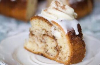 A delectable cinnamon roll bundt cake that combines the comforting flavors of a classic cinnamon roll with the elegant presentation of a bundt cake. This moist and flavorful cake features layers of cinnamon sugar swirled throughout the batter, reminiscent of the beloved spiral found in traditional cinnamon rolls. The cake is often topped with a luscious cream cheese glaze, adding a sweet and tangy finish that complements the warm cinnamon spice. To enhance the visual appeal, a sprinkle of chopped nuts or a dusting of powdered sugar may be added. This cinnamon roll bundt cake offers all the goodness of a cinnamon roll in a convenient and shareable form, making it a delightful centerpiece for brunches, celebrations, or any occasion where a touch of comforting sweetness is desired.
