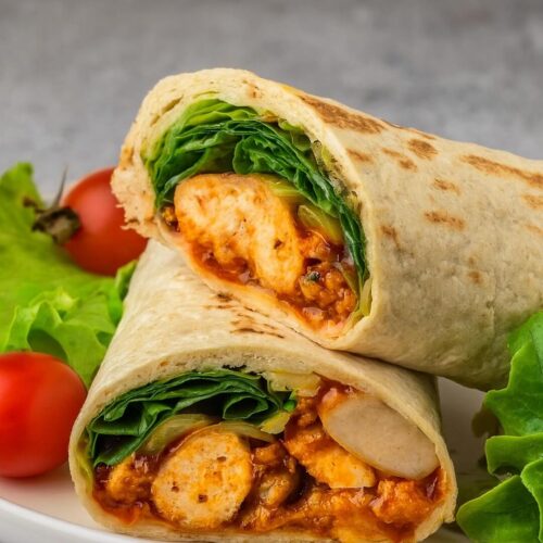 The popular Buffalo Chicken Wrap features tender buffalo chicken on a bed of crisp vegetables, topped with cheese and creamy dressing, all wrapped snugly in a tasty flour tortilla.