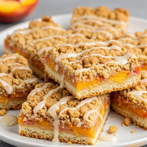 Sweet, juicy peaches baked between layers of buttery cinnamon crumb—these peach crumb bars are a slice of summer in every bite!