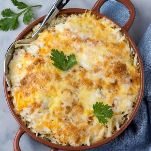 This Chicken and Rice Casserole combines creamy cheese, tangy tomatillo salsa, savory rotisserie chicken, and hearty rice. With layers of flavor from the refried beans, charred corn, and green chiles, this casserole is a comforting, well-rounded dish perfect for weeknight dinners or gatherings. Garnished with fresh scallions and cilantro, it’s both visually appealing and deliciously satisfying.