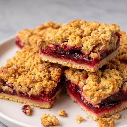 Cranberry Crumble Bars are a delightful balance of tart and sweet, featuring a buttery oat crust, a tangy cranberry filling with a hint of orange, and a lightly sweet orange glaze. Perfect for festive gatherings or as a vibrant treat any time of year!