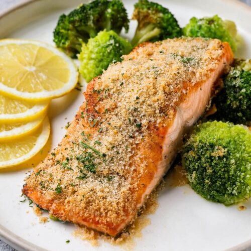 Parmesan Crusted Salmon with Roasted Broccoli features succulent salmon with a golden, cheesy crust infused with lemon, thyme, and fresh parsley. Roasted broccoli on the side, seasoned with garlic, olive oil, and black pepper, rounds out this satisfying, balanced meal.